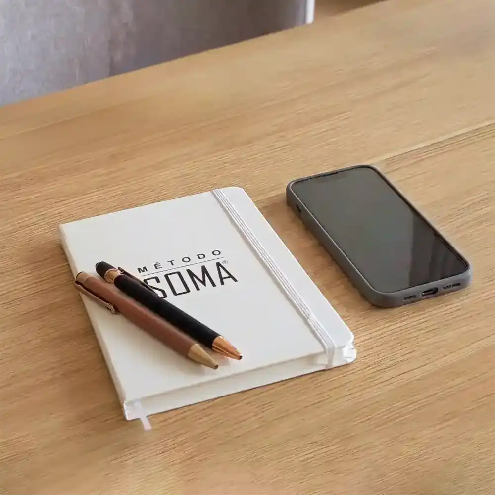 Cuaderno y teléfono preparados para una sesión de Método Soma® a distancia